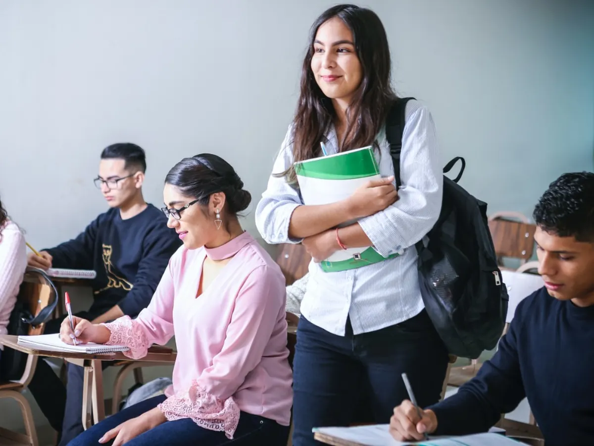 Estudiante de bachillerato con sus cuadernos en el aula junto a sus compañeros